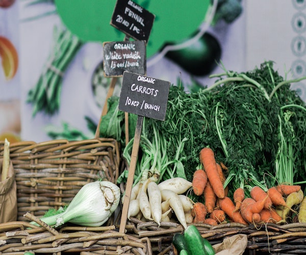 a picture of carrots in a wood basket with a sign sticking out of it that says carrots.